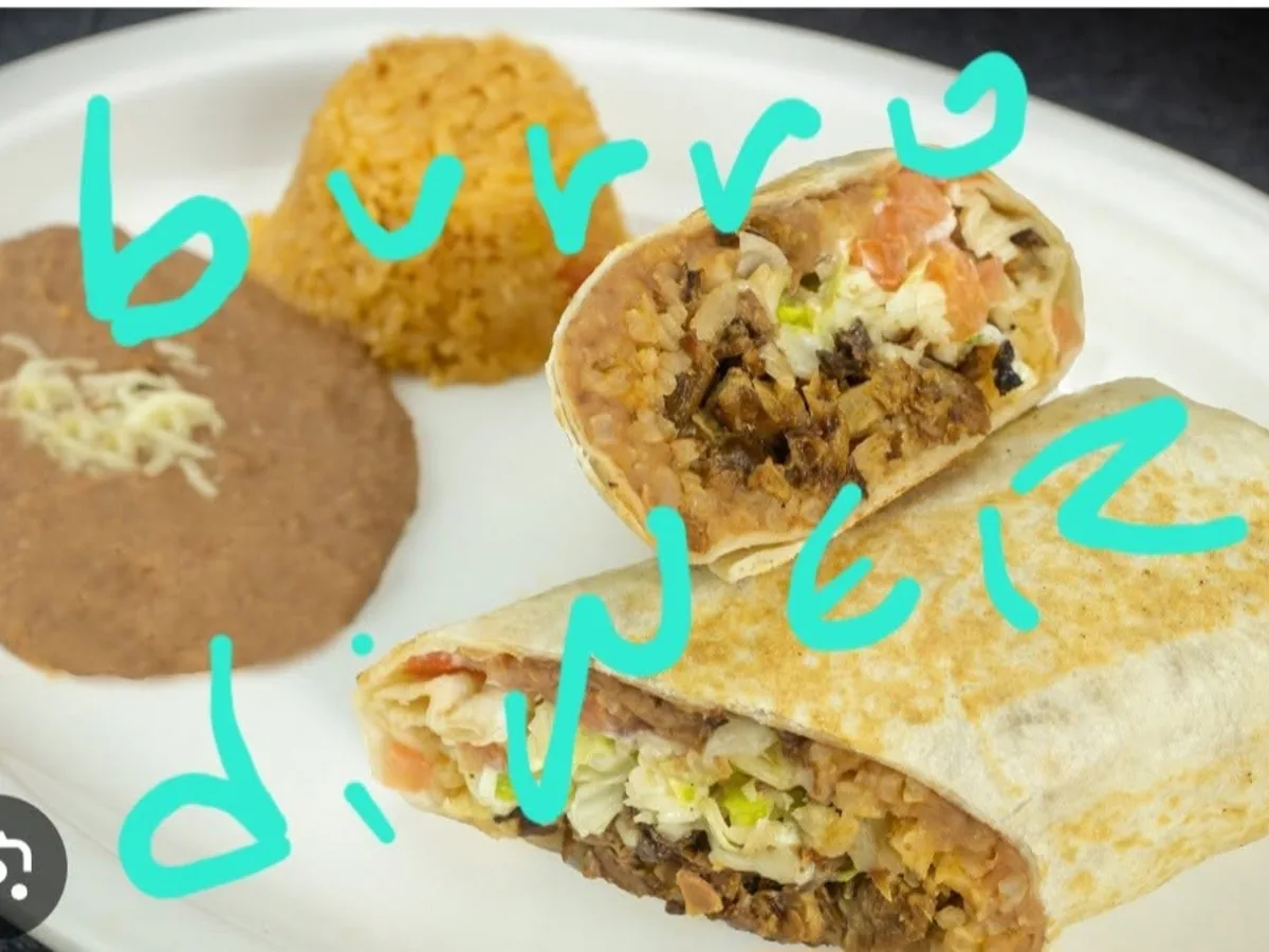 Burrito cut in half on a plate with Spanish rice and refried beans