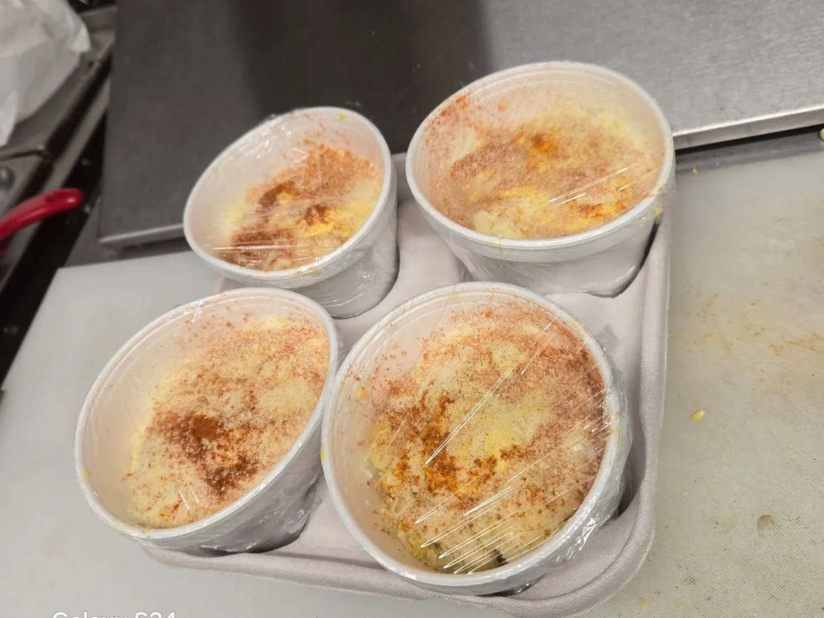 Elote en vaso topped with mayonnaise, cheese and chili powder