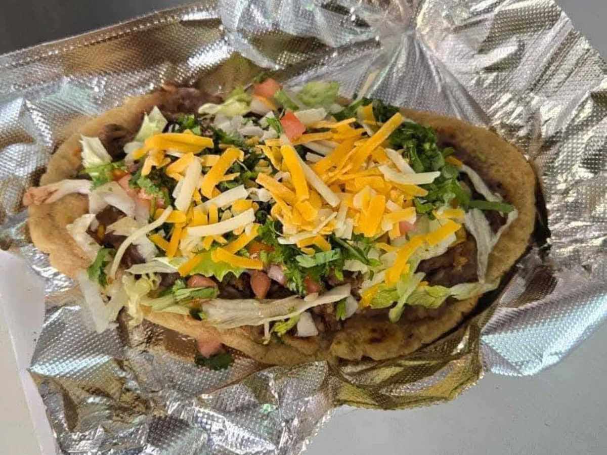 Huarache topped with meat, lettuce, shredded cheese and pico de gallo