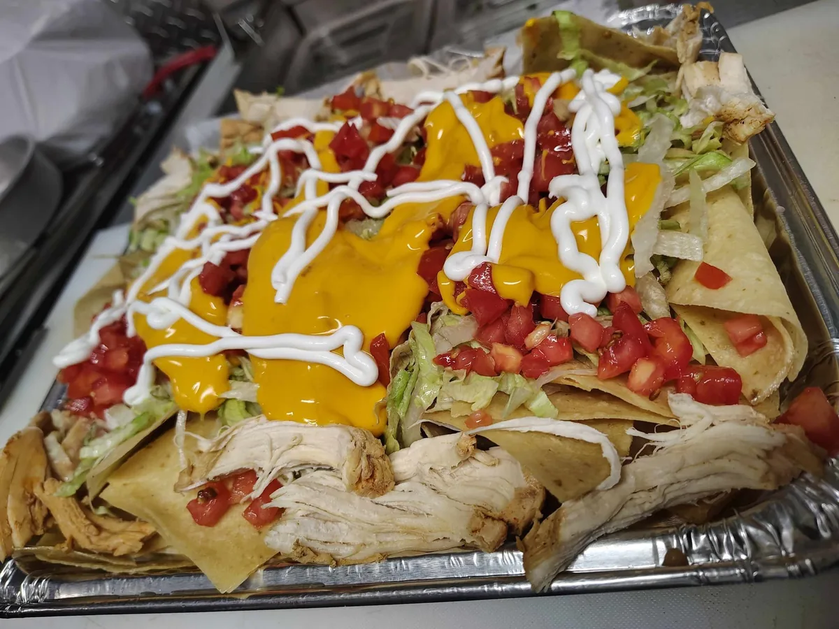 Nachos con pollo loaded with cheese sauce, lettuce, pico de gallo and sour cream