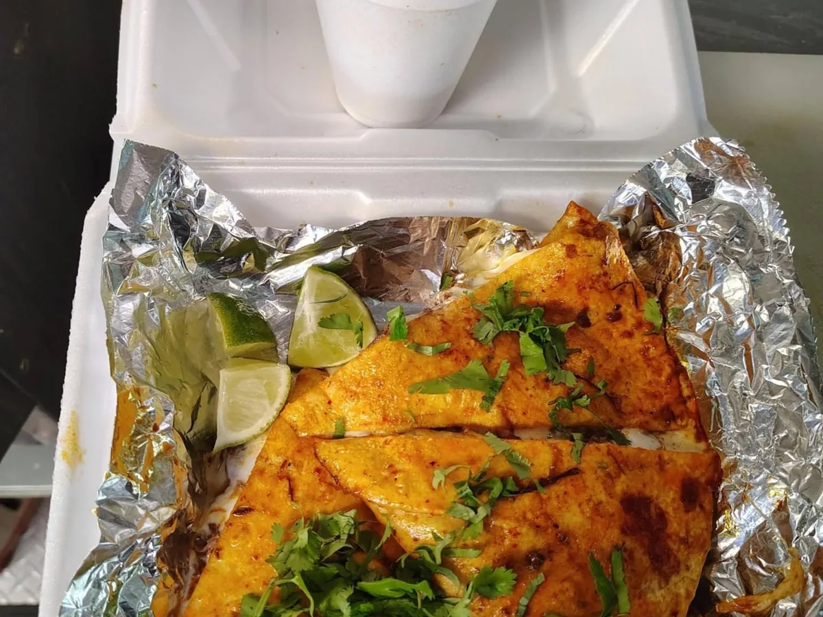 Quesadilla de birria cut into wedges with cilantro and lime