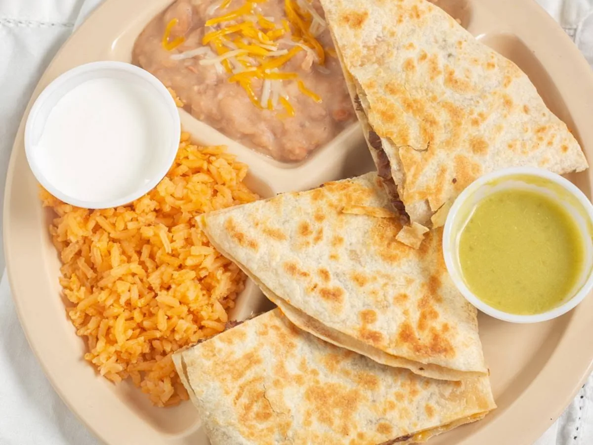 Quesadilla plate with rice, refried beans, sour cream and salsa verde