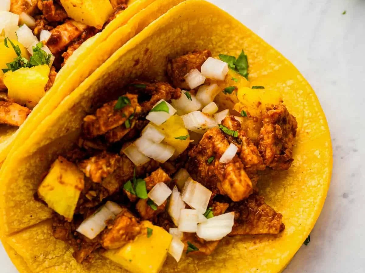Taco al pastor con piña topped with pineapple, onion and cilantro